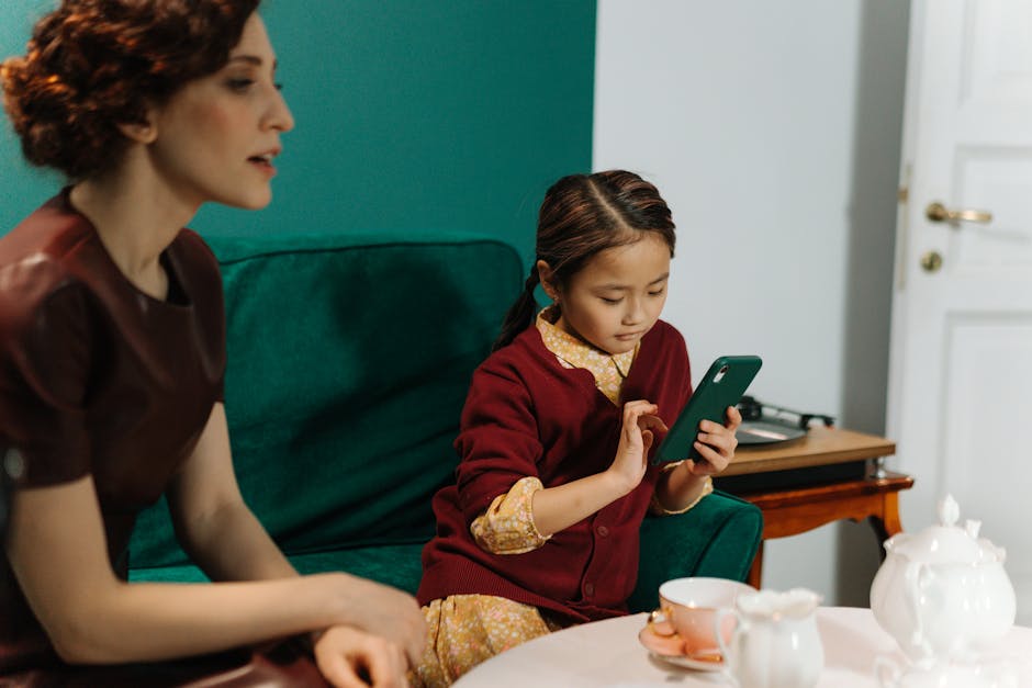 A woman and child sitting in a living room using a smartphone together.